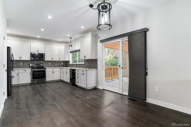 a kitchen with stainless steel appliances granite countertop a stove top oven a sink and white cabinets with wooden floor