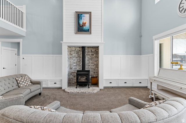 1426 South 1450th Street West Mapleton, UT 84664 - Photo 6 of 50 Living area featuring a floor-to-ceiling shiplap fireplace surround with a brick-lined hearth and wood-burning stove