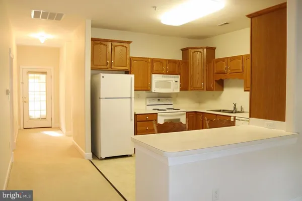 a kitchen with a refrigerator a stove top oven and cabinets