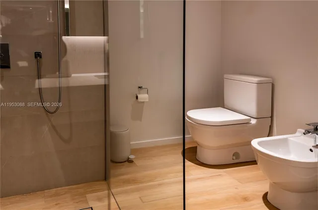 a white toilet sitting next to a bathroom sink and a shower