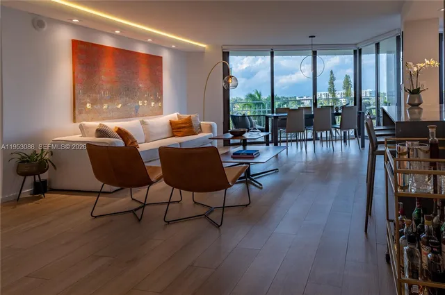 a living room with furniture a large window and wooden floor