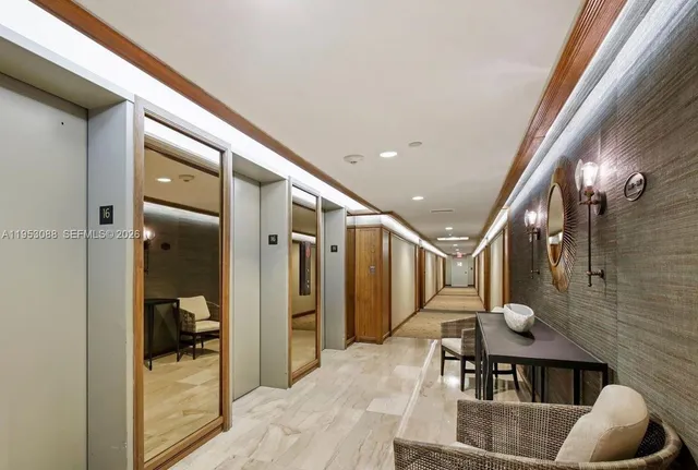 a hallway with white cabinets and chandelier