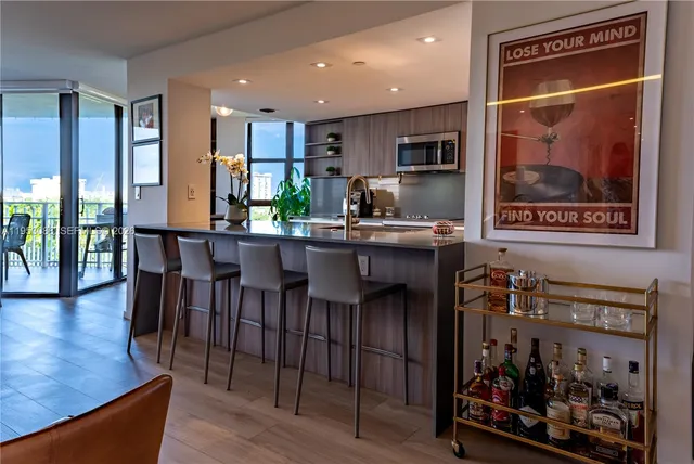 a dining hall with stainless steel appliances granite countertop a refrigerator and a dining table with wooden floor