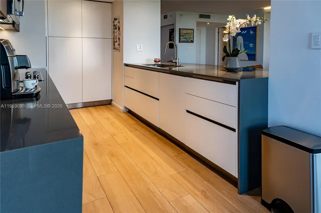 a room with kitchen island a sink wooden floor and white appliances