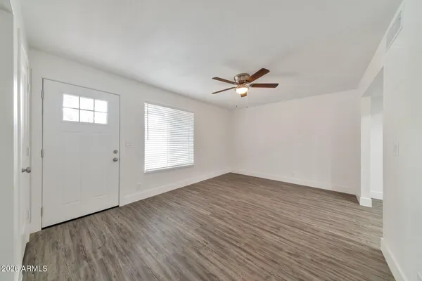 a view of an empty room with a window and wooden floor