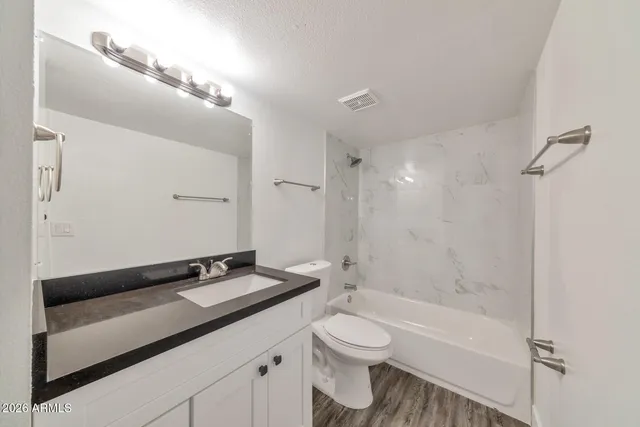 a bathroom with a granite countertop sink a toilet and shower