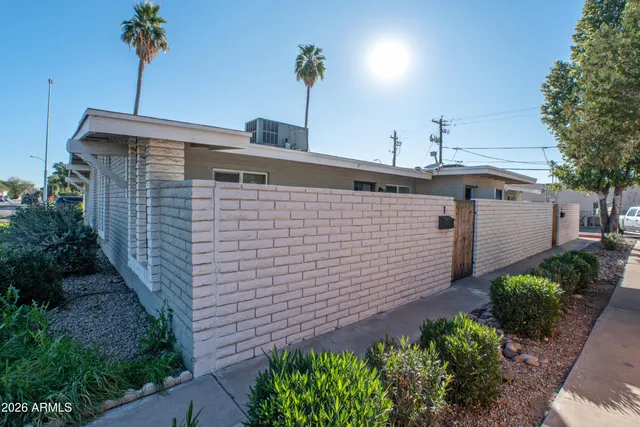 a front view of a house with a yard and potted plants