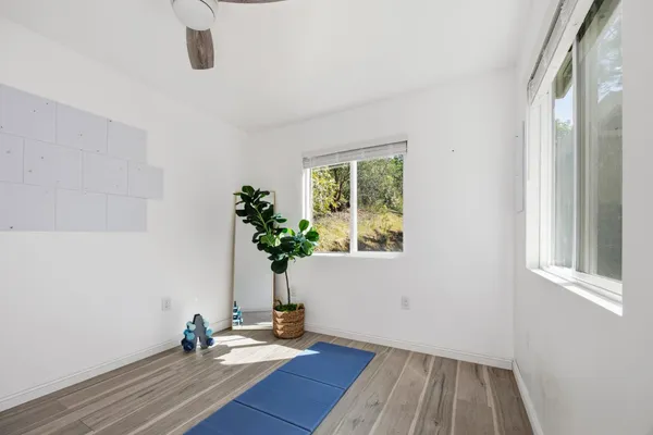 a view of an empty room with a window and wooden floor
