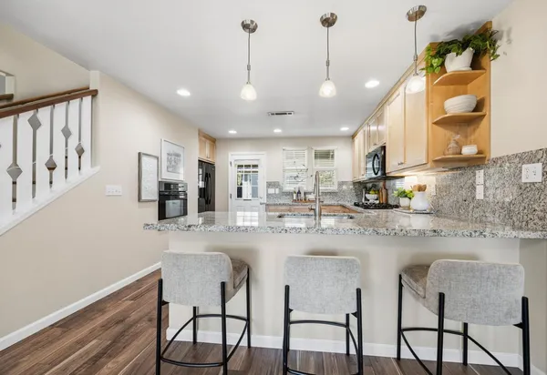 a kitchen with stainless steel appliances granite countertop a dining table chairs and white cabinets