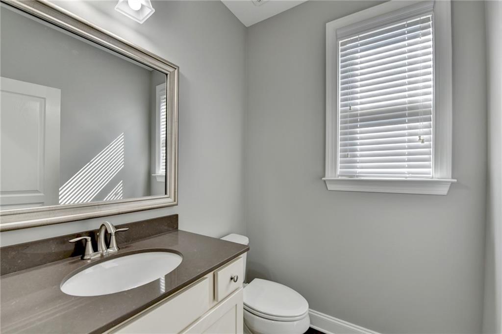 4217 Heisenberg Lane Suwanee, GA 30024 - Photo 15 of 72 a bathroom with a granite countertop sink toilet a mirror and a window