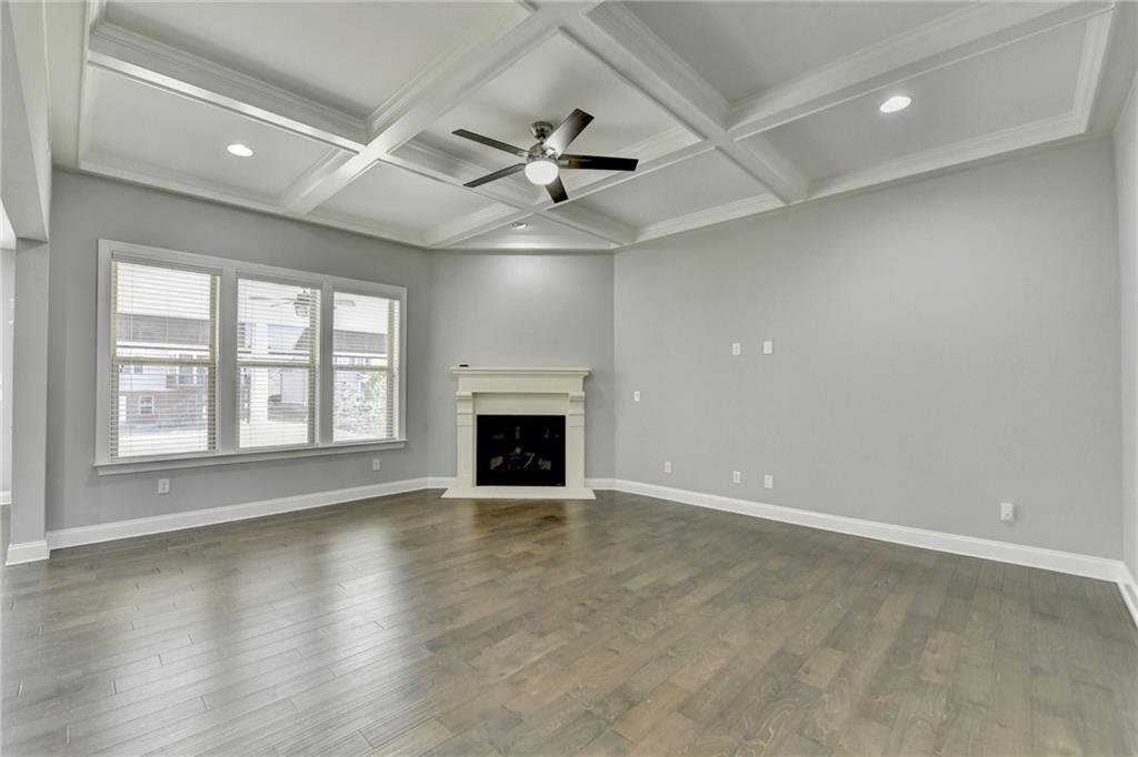 4217 Heisenberg Lane Suwanee, GA 30024 - Photo 17 of 72 an empty room with windows fireplace and a ceiling fan