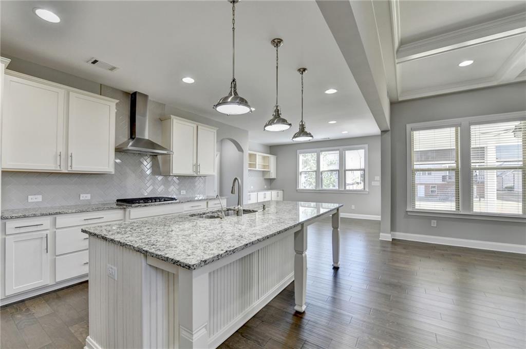 4217 Heisenberg Lane Suwanee, GA 30024 - Photo 24 of 72 a kitchen with stainless steel appliances granite countertop a sink a stove and a wooden floors