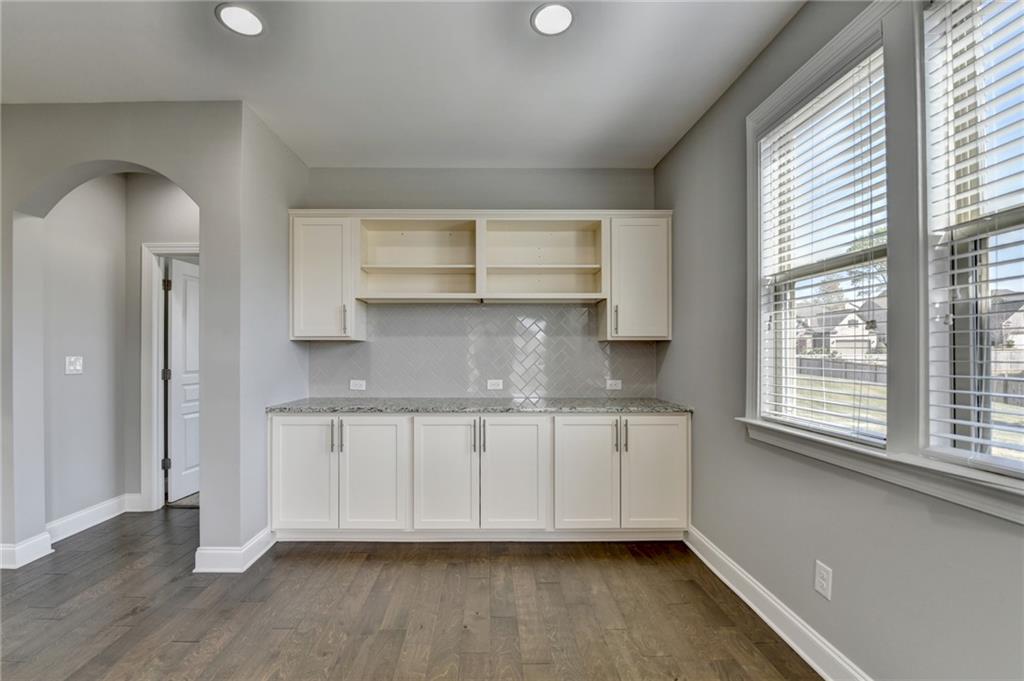 4217 Heisenberg Lane Suwanee, GA 30024 - Photo 32 of 72 a kitchen with granite countertop white cabinets and wooden floor