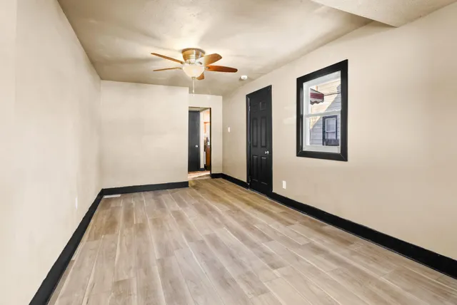 a view of an empty room with wooden floor and a window