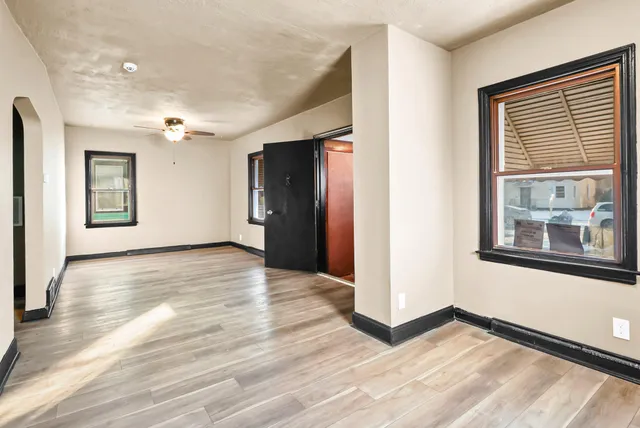 a view of an empty room with window and wooden floor