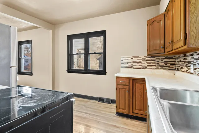 a kitchen with stainless steel appliances granite countertop a refrigerator a sink dishwasher and wooden cabinets with wooden floor