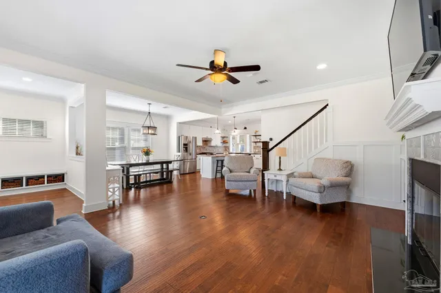 a living room with couches and a view of kitchen with wooden floor