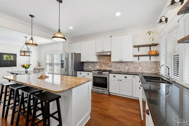 a open kitchen with stainless steel appliances granite countertop a stove a sink dishwasher a refrigerator with a table and chairs