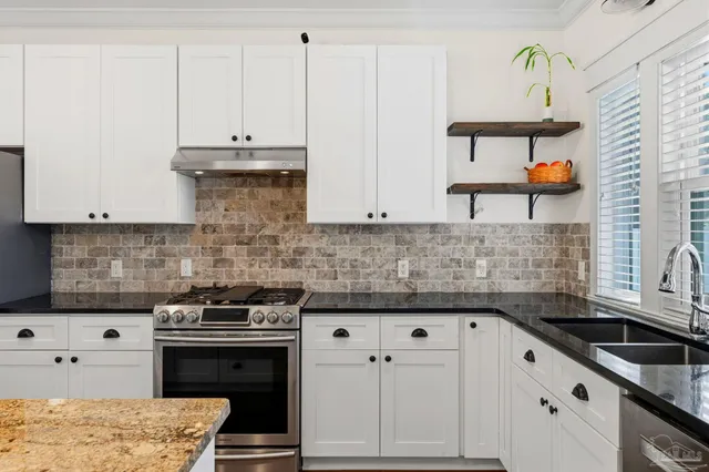 a kitchen with stainless steel appliances granite countertop a stove a sink and a white cabinets