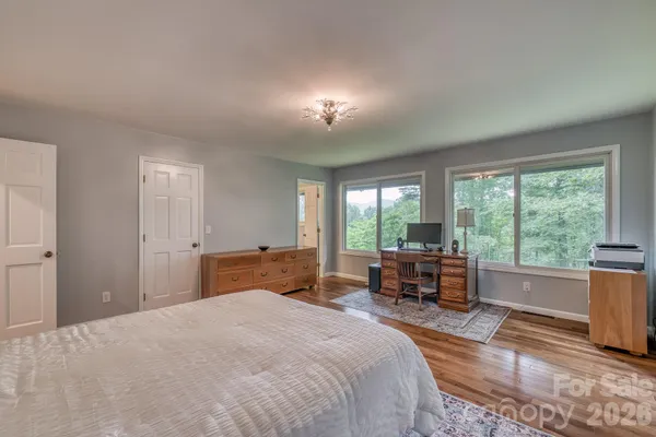 a bedroom with a bed and large windows