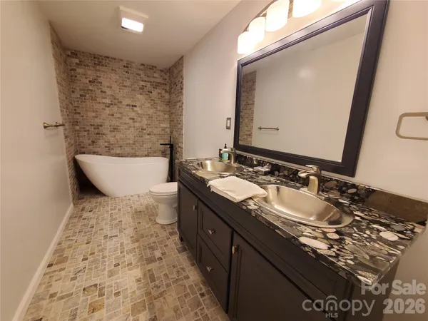 a bathroom with a granite countertop sink a toilet a mirror and bathtub