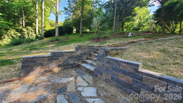 a view of a house with a yard and a large tree