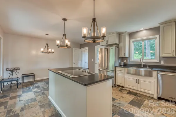 a kitchen with stainless steel appliances granite countertop a sink a island a stove and a window
