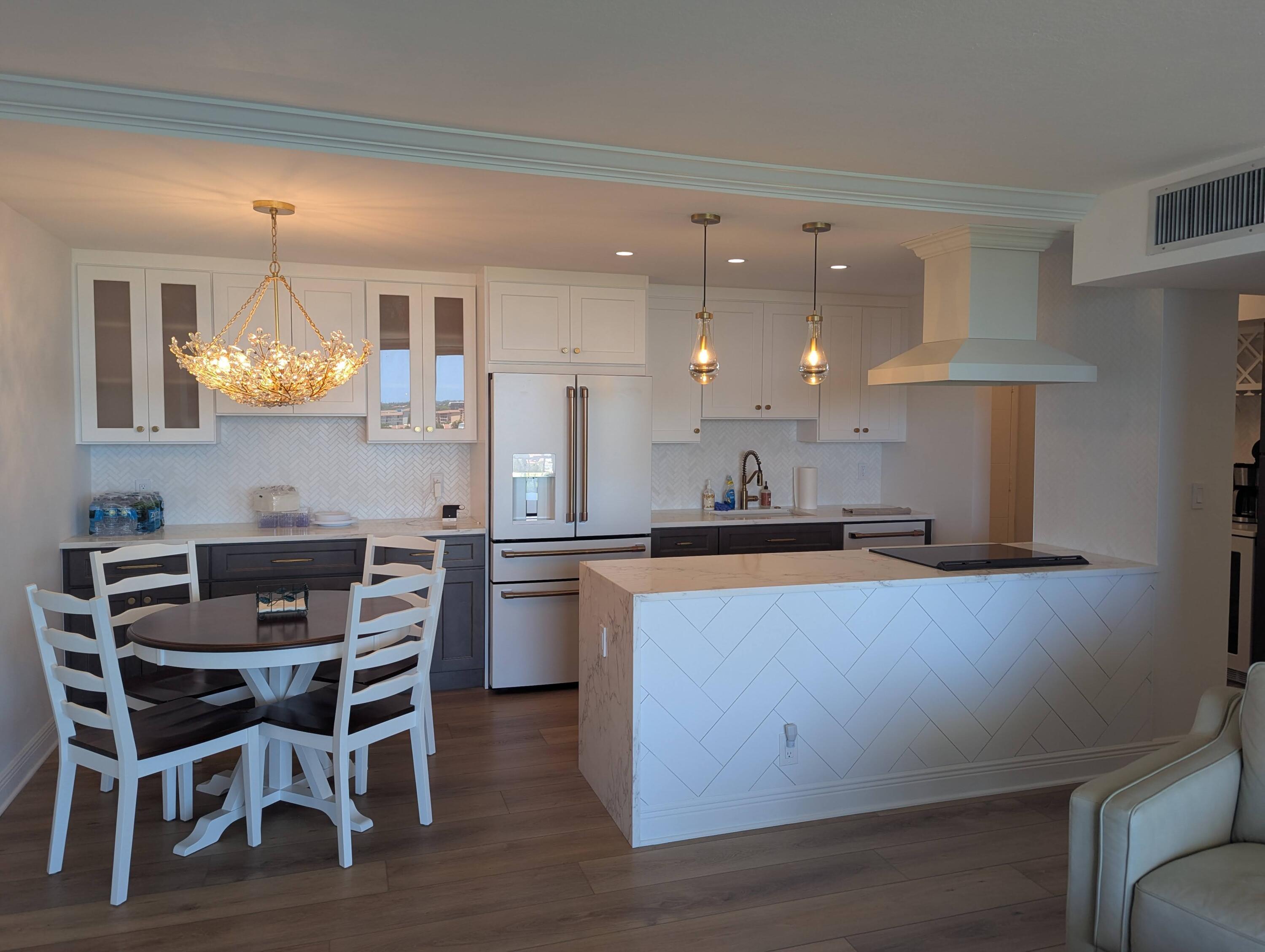 2121 North Ocean Boulevard, Unit 1006E Boca Raton, FL 33431 - Photo 10 of 64 a kitchen with stainless steel appliances kitchen island granite countertop a table chairs sink and cabinets