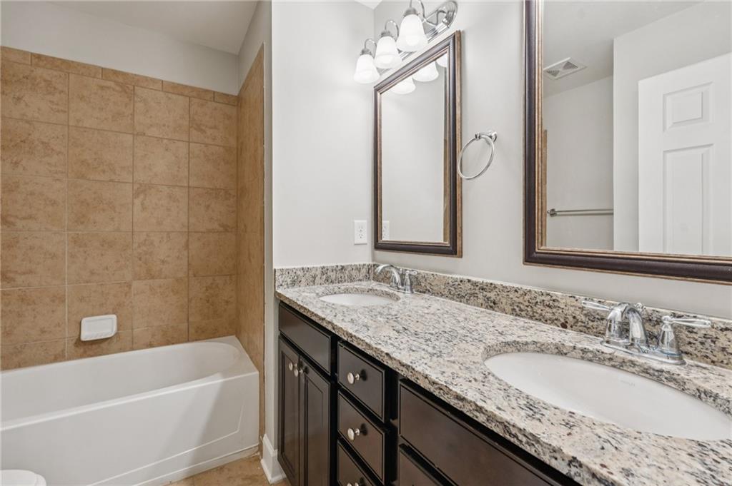 1514 Woodbridge Way Northeast Atlanta, GA 30329 - Photo 42 of 54 a bathroom with a granite countertop bathtub a sink and a mirror