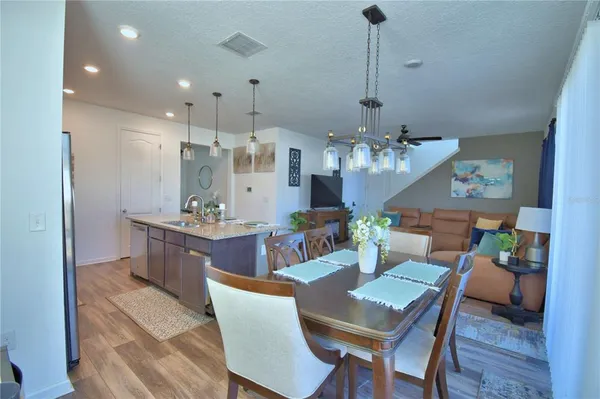 a view of a dining room and livingroom with furniture wooden floor a chandelier