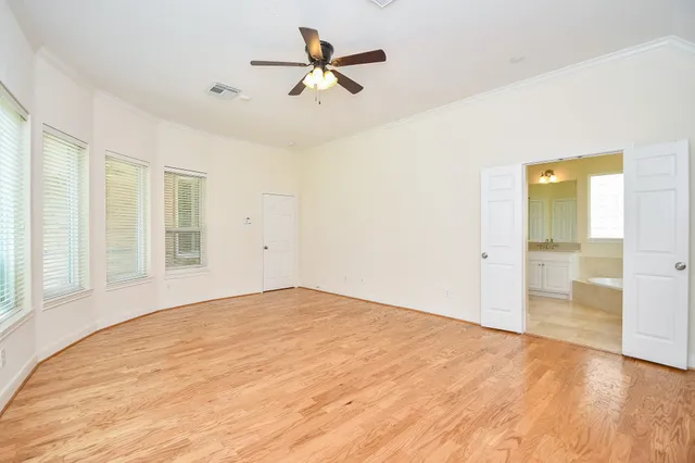 a view of empty room with wooden floor and ceiling fan