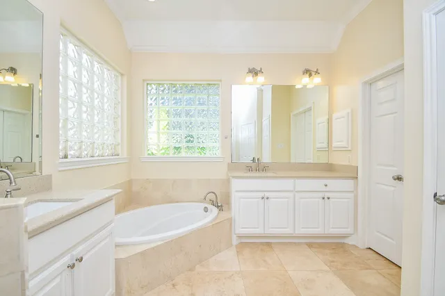 a spacious bathroom with a tub sink and mirror