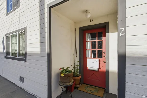 a front view of a house with a entryway door and potted plants