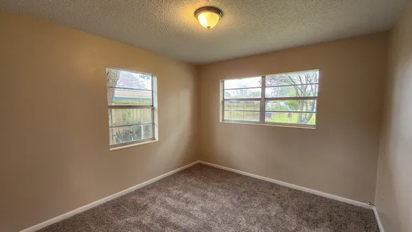 a view of an empty room with window and closet area
