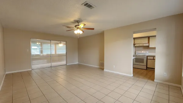 an empty room with windows and ceiling fan