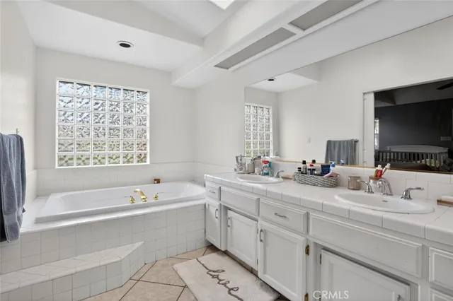 a bathroom with a tub a double vanity sink and mirror