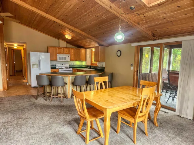 a dining room with stainless steel appliances a table chairs and a chandelier