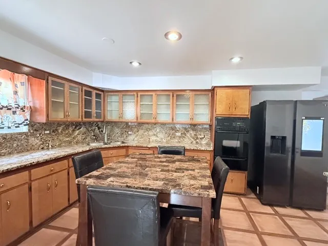 a kitchen with granite countertop a stove a refrigerator and a counter space