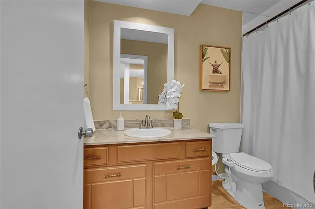 a bathroom with a granite countertop toilet sink and mirror