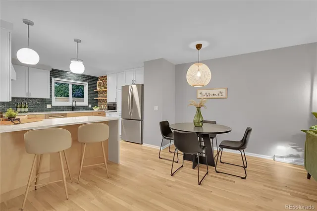 a dining room with wooden floor a chandelier a wooden table and chairs