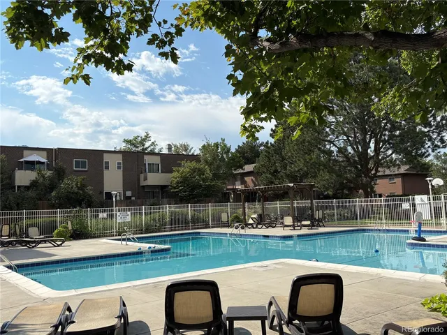 a view of a swimming pool and lounge chairs in back yard