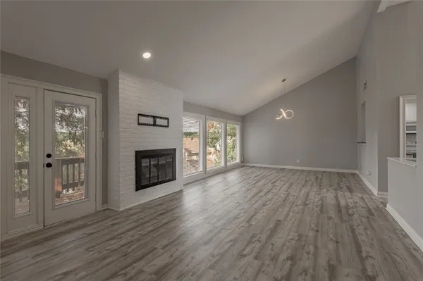 an empty room with wooden floor fireplace and windows