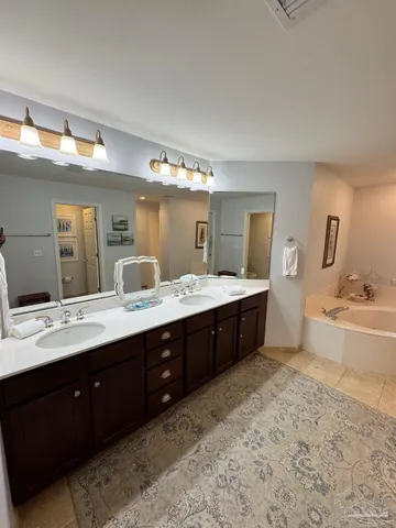 a spacious bathroom with a double vanity sink a mirror and a bathtub