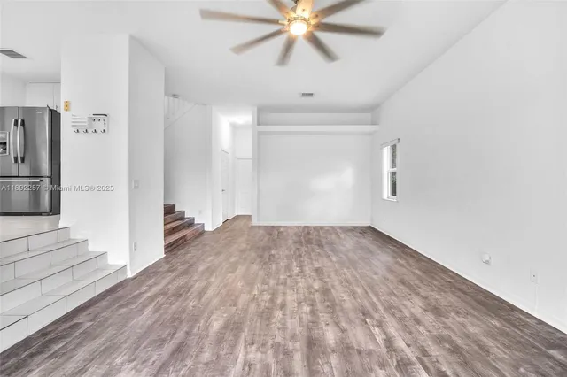 a view of a livingroom with wooden floor and a ceiling fan