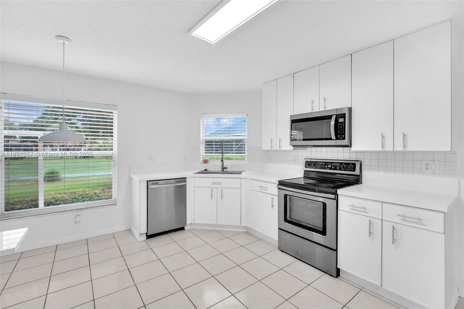 1637 Southwest 156th Avenue Pembroke Pines, FL 33027 - Photo 7 of 27 a kitchen with a stove a sink and a microwave