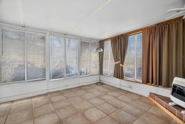 a view of an empty room with window and ceiling fan