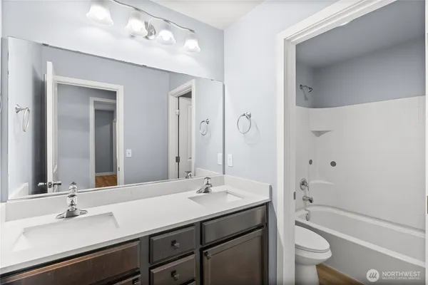a bathroom with a granite countertop sink a toilet and a large mirror