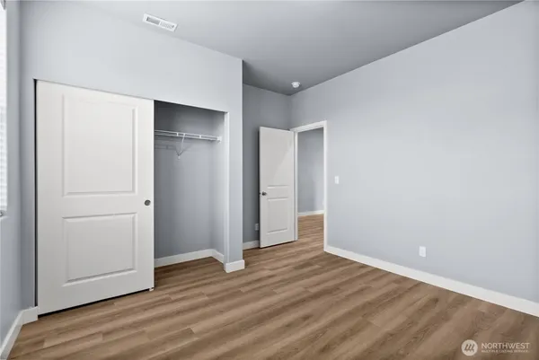 a view of an empty room with wooden floor and closet