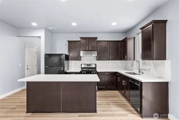 a kitchen with kitchen island a sink dishwasher a refrigerator and a stove with wooden floor