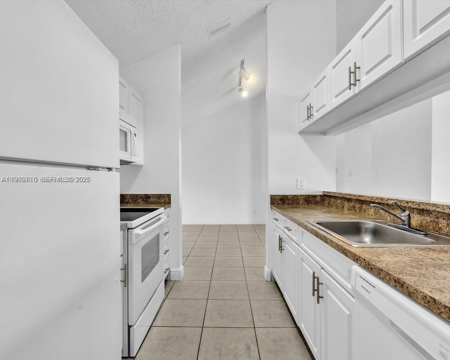 15770 Southwest 106th Terrace, Unit 303 Miami, FL 33196 - Photo 11 of 64 a kitchen with granite countertop a sink and a stove with wooden floor